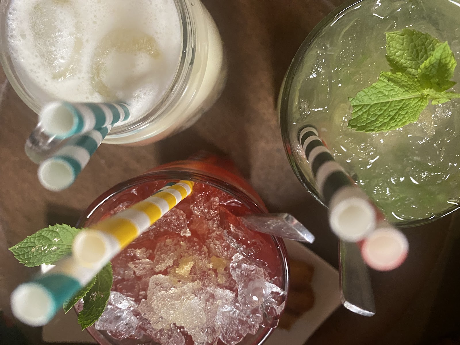 Trois cocktails colorés avec pailles rayées et menthe fraîche vus du dessus